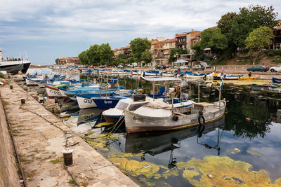 Boats moored at harbor against buildings in city