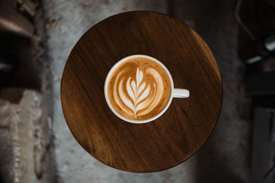 Latte art coffee on wooden table in coffee shop