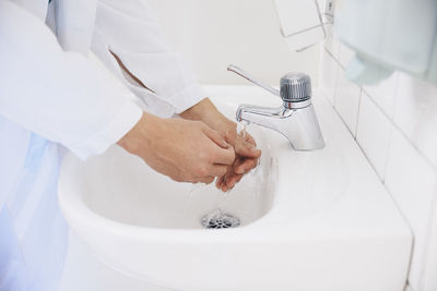 Cropped of male doctor washing hands in sink at hospital