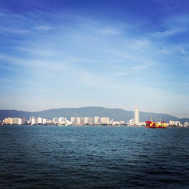 waterfront, water, architecture, sea, built structure, sky, building exterior, transportation, rippled, blue, river, nautical vessel, city, cloud - sky, mid distance, nature, tranquil scene, connection, scenics, cloud