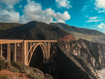 Arch bridge over mountains against sky