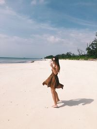Side view of young woman standing at beach