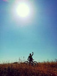 Silhouette man riding motorcycle on field against clear sky