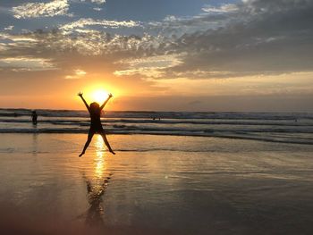 Silhouette man standing at beach against sky during sunset