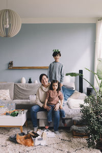 Portrait of happy family collecting waste in living room at home