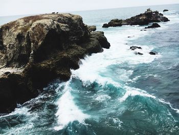 Rock formation in sea against sky