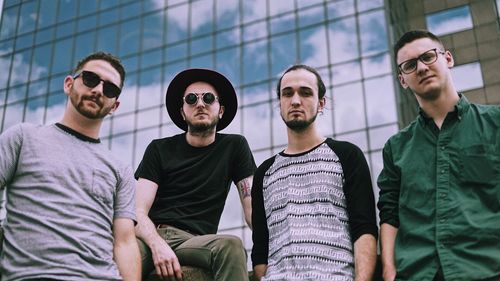 Low angle portrait of male friends standing against building