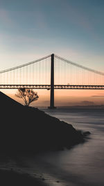 Bridge over sea against sky during sunset