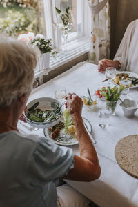 Smiling senior woman having meal at table