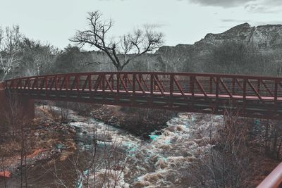 Railroad tracks by bare trees against sky