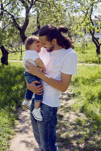 Father holds son in his arms in a blooming garden