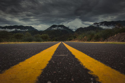 Surface level of road by mountains against sky