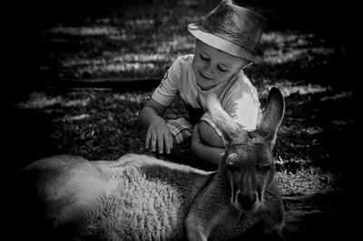 Cute boy touching kangaroo on field