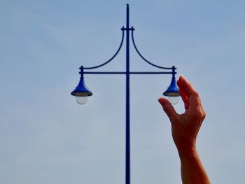 Optical illusion of hand holding street light against clear blue sky