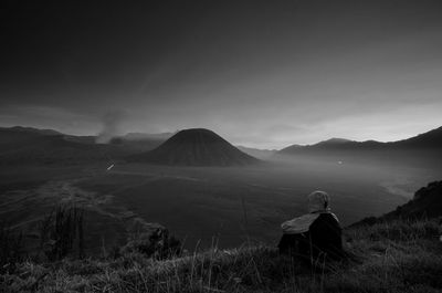 Scenic view of person sitting on land against sky