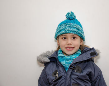 Portrait of smiling girl wearing warm clothing against white background