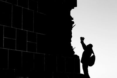 Low angle view of silhouette man standing by wall