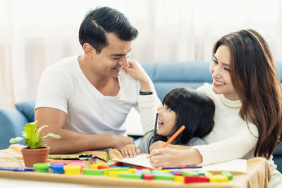 Smiling girl with parents in living room at home