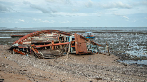 Abandoned motorcycle on beach against sky