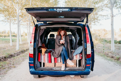 Woman holding mug while sitting in camper trailer