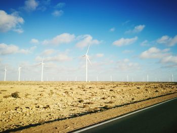 Wind turbines on field against sky