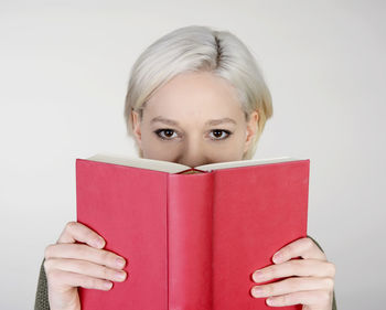 Portrait of a girl holding book against white background