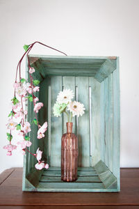 Flower vase on wooden table against wall