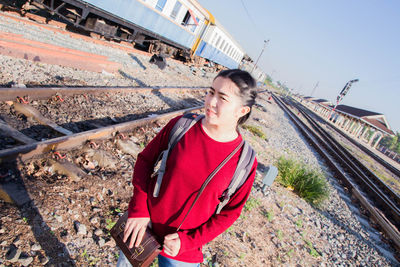 Young man on railroad tracks against sky