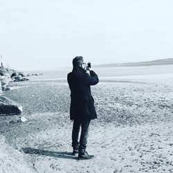 Rear view of man taking photo on beach