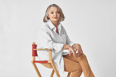 Woman sitting on chair against white background