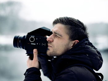 Profile view of man photographing with camera during winter