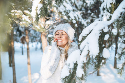 Portrait of young woman standing against trees