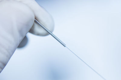 Cropped hand holding acupuncture needle in hospital