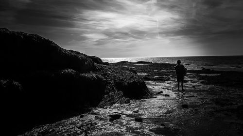 Silhouette man standing on beach against sky