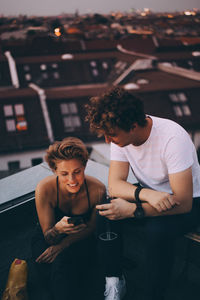 Young man using smart phone while sitting in laptop