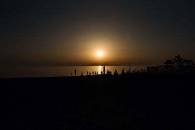 Silhouette people on beach against clear sky during sunset