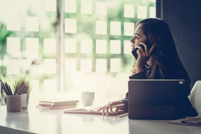 Businesswoman talking over smart phone while sitting in office