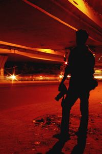 Silhouette man standing on illuminated road at night