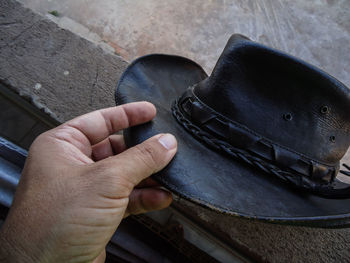 Holding the brim of a brown leather hat
