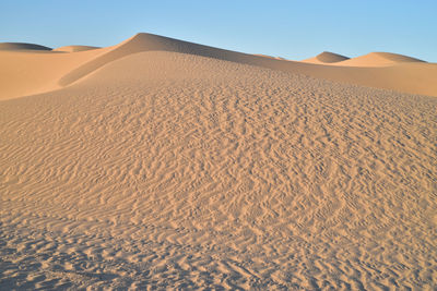 Sand dune in desert against clear sky