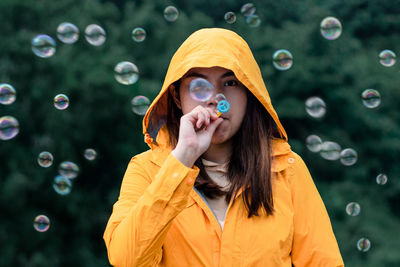 Portrait of young woman looking away while standing against bubbles