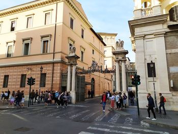 People walking on road against buildings in city