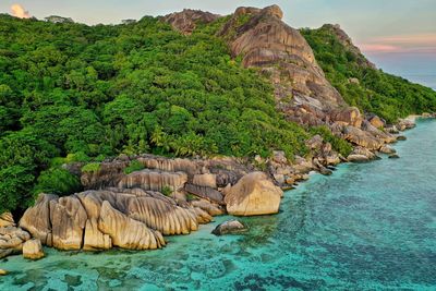 Scenic view of rocks by sea against sky