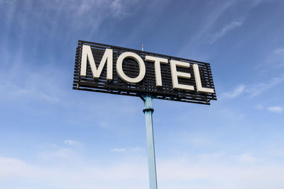 Low angle view of road sign against blue sky