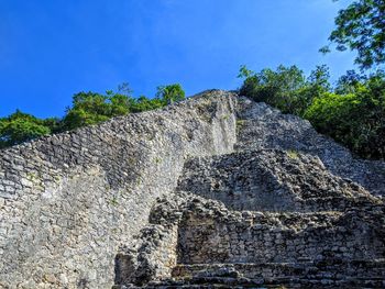 Low angle view of weathered wall against blue sky