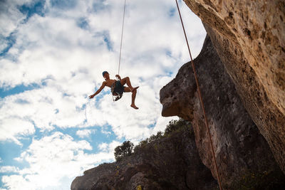 Low angle view of person on rock against sky