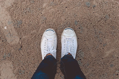 Low section of man standing on sand