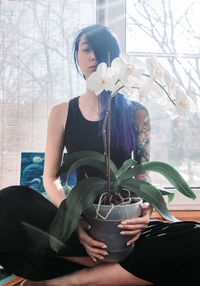 Young woman sitting on window sill