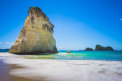 Rock formations in sea against blue sky