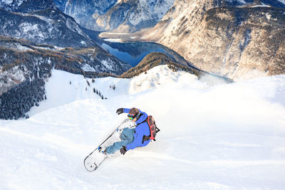 Man snowboarding on snowcapped mountain against sky